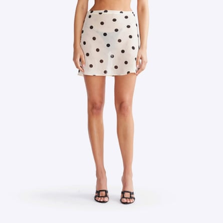 A model wears a white semi-opaque miniskirt with black polka dots and black underwear.