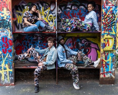 Four models sitting in graffitied cubicles wearing highly patterned garments
