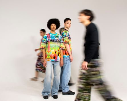Three models wearing bright, highly patterned garments, the one in the foreground blurred