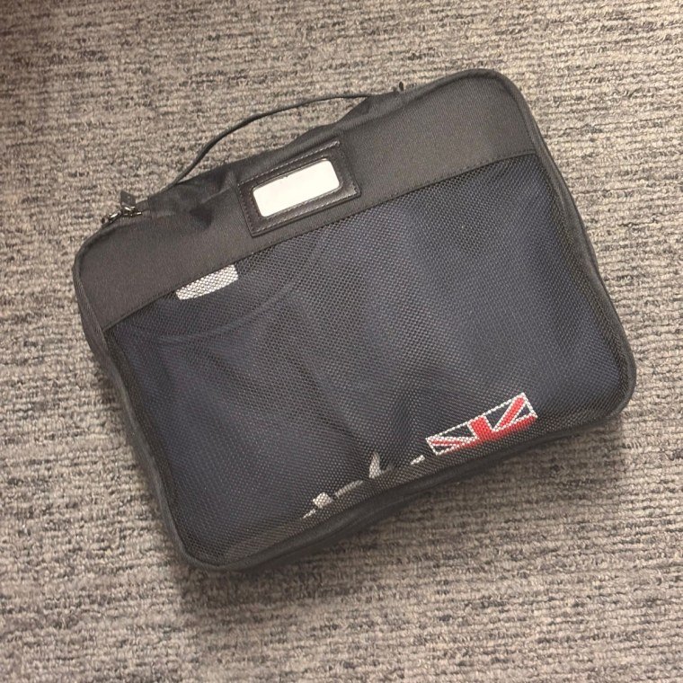 Small Calpak packing cube packed with a sweater on carpet.