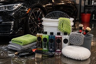 Car wash kit with detailing supplies beside a freshly cleaned black car