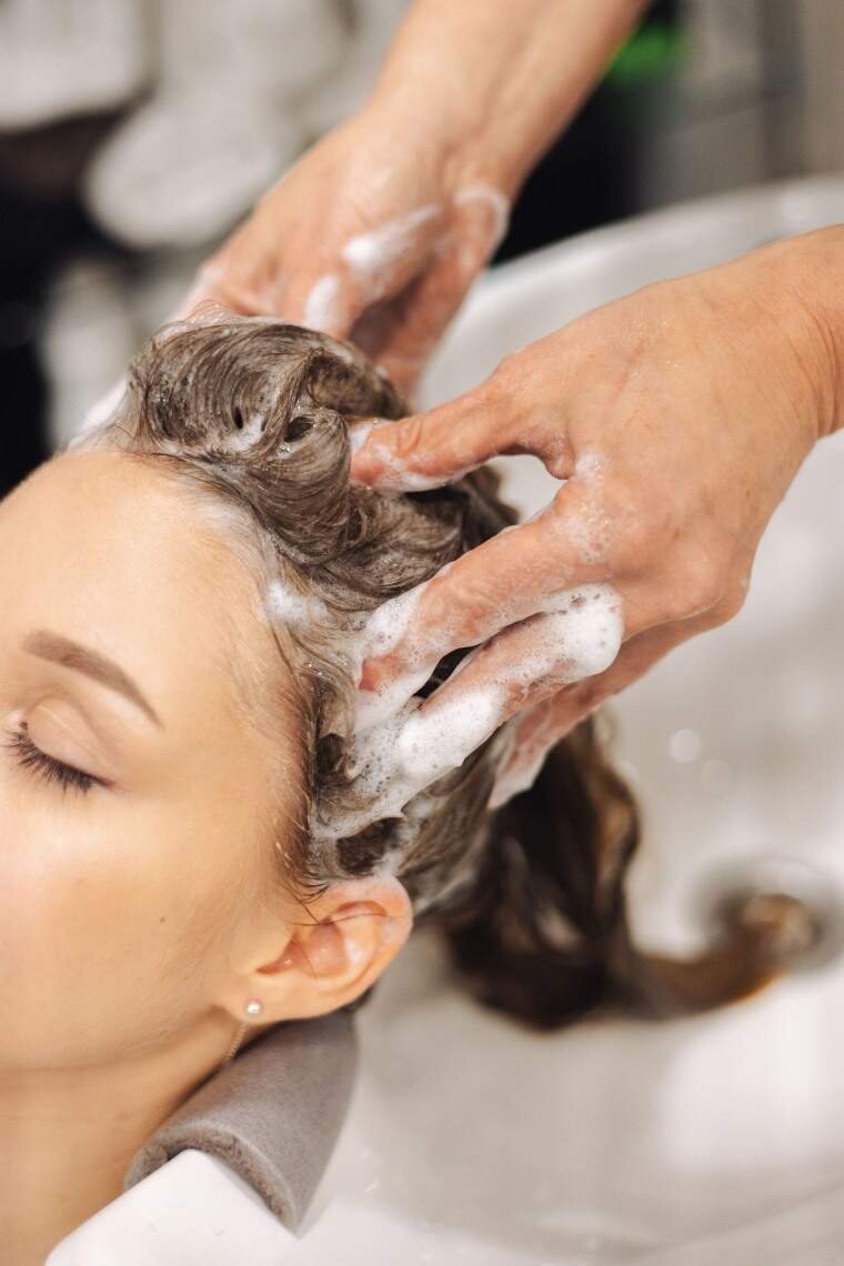 A woman washing her hair with hair care products.