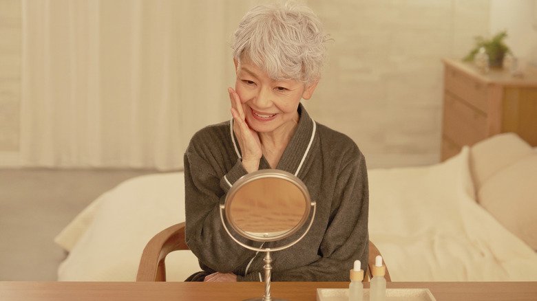 An older woman smiling as she looks in the mirror