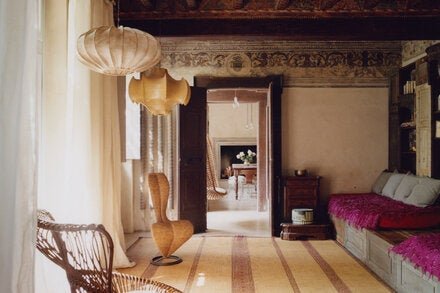 In the living room of the stylist and interior designer Paola Moretti’s home in Brescia, Italy, which was formerly a rectory attached to a Romanesque church, filikli blankets from Altai and Rachtian Gallery on custom-designed sofas, shelves made of wood salvaged during the church’s restoration, linen cushions by Society Limonta, a Tuareg mat from Altai, a chair by Tom Dixon for Cappellini, a Bonacina armchair by Franco Albini and a vintage ceiling lamp by the Castiglioni brothers for Flos.