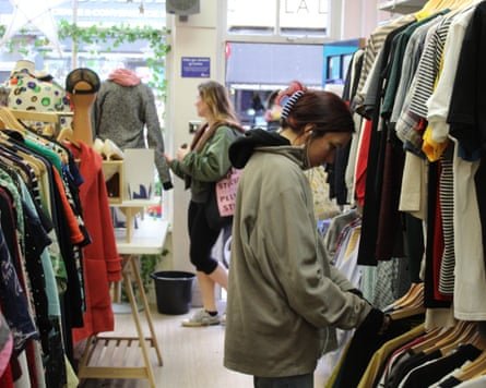 A person looks through a charity shop clothing rail