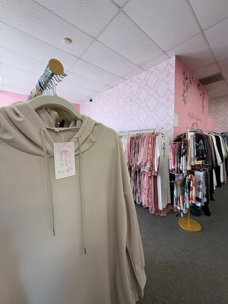 A long tan sweatshirt hangs on a rack in a clothing store.