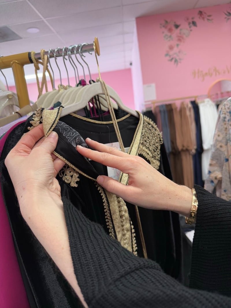 A woman showcases the embroidery on a piece of clothing.
