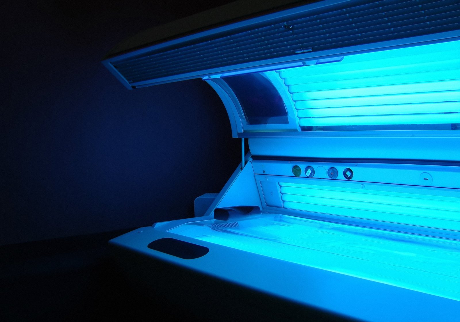 Open tanning bed with glowing blue light, commonly used for indoor tanning and potentially linked to skin health concerns