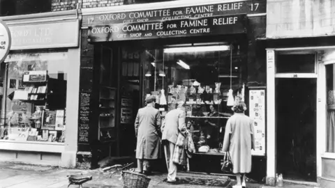 Oxfam A black and white archive image of shoppers peering through the windows of Oxfam's Broad Street shop